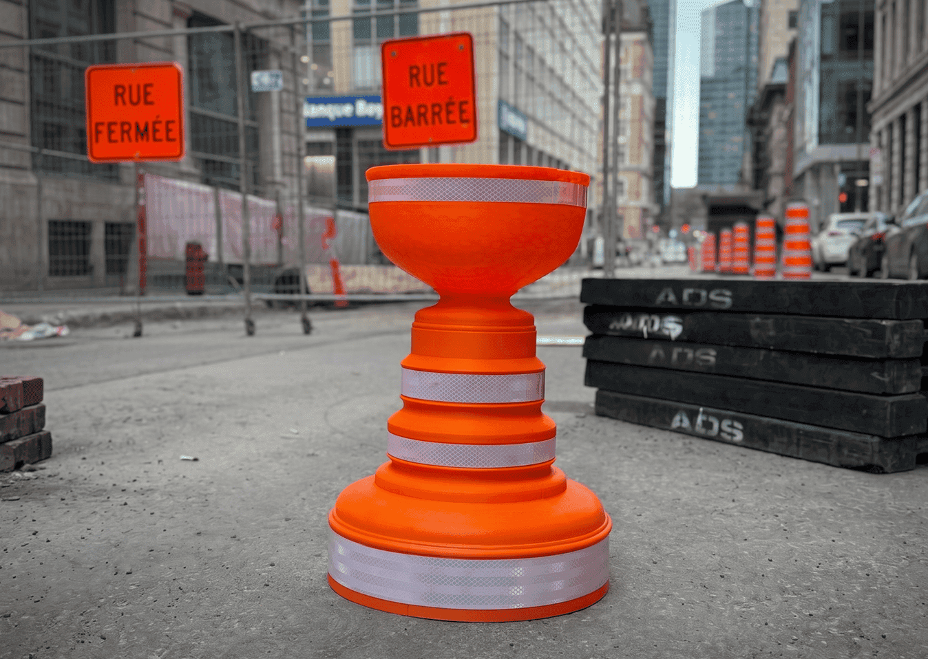 Orange traffic cone blocking street in construction zone.
